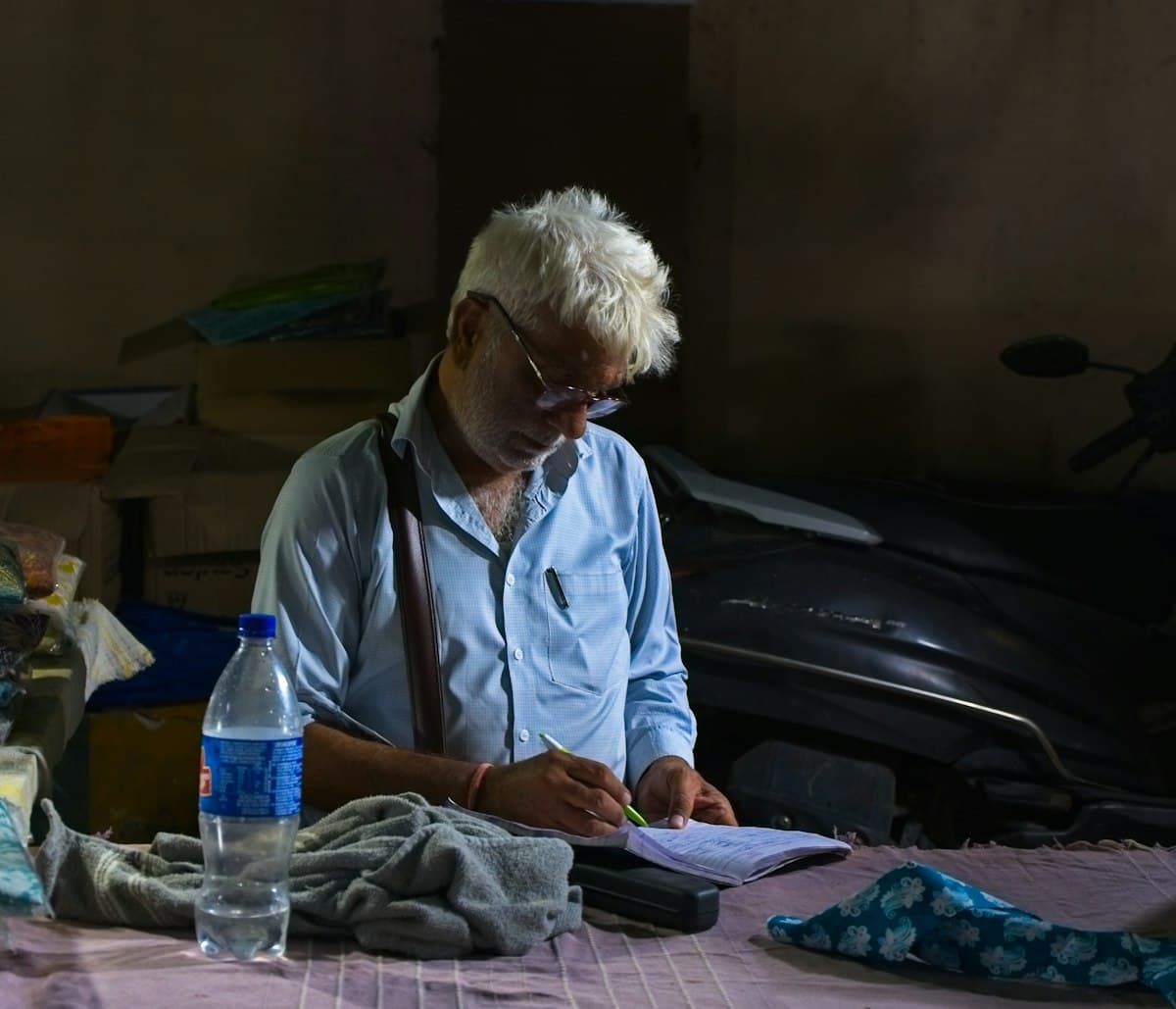 A shopkeeper doing hisab-kitab by hand in a paper register